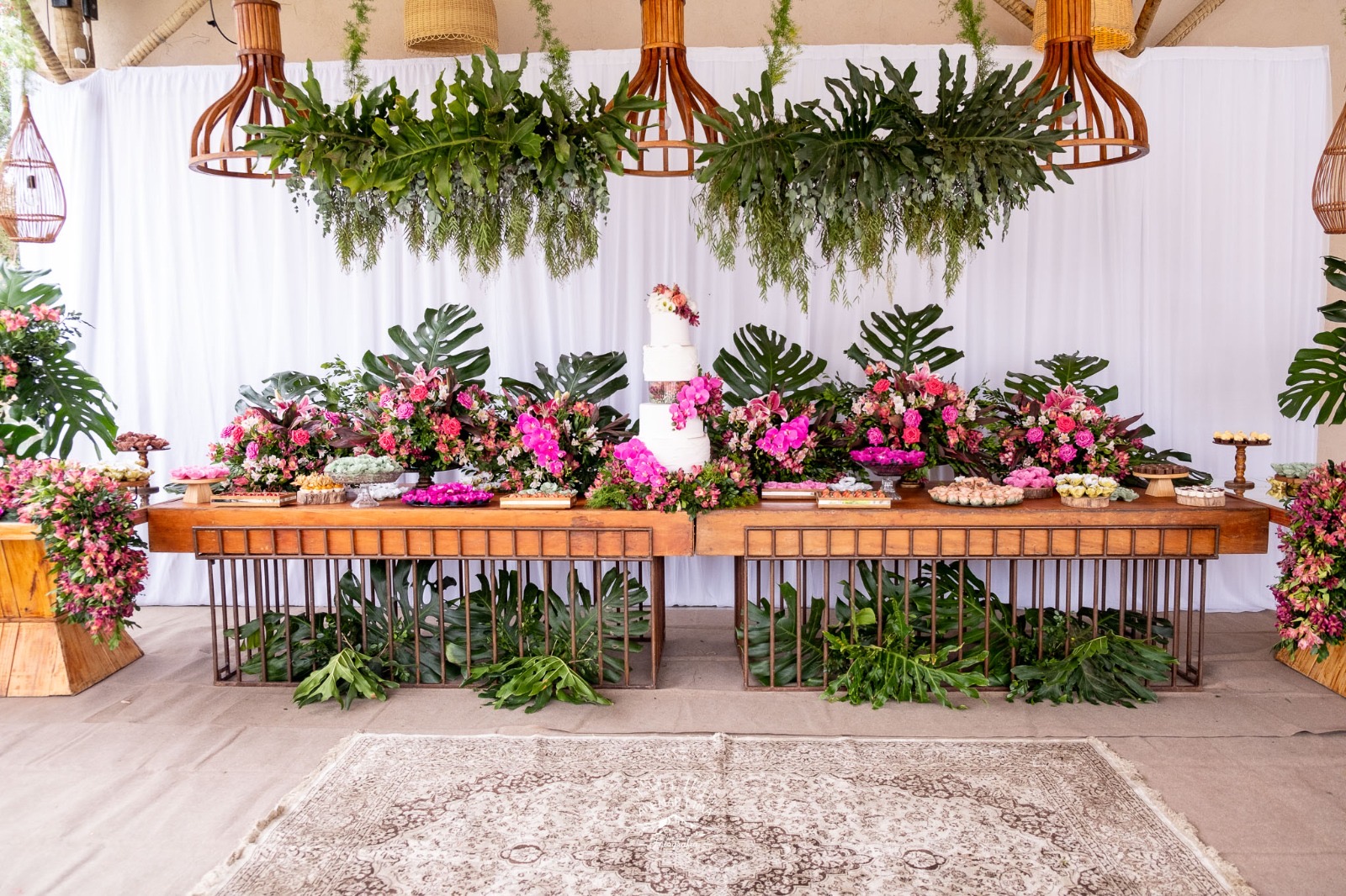 Mesa de doces de casamento decorada com flores e forminhas artesanais